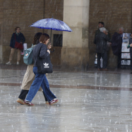 Fotografía de archivo de dos viandantes caminando bajo la lluvia.