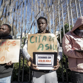 Varios solicitantes de protección internacional sujetan pancartas durante una concentración.