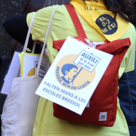 Una treballadora porta un cartell penjat a la motxilla amb l'advertència "falten mans a les escoles bressol", en una protesta de la plantilla de l’Ajuntament de Barcelona