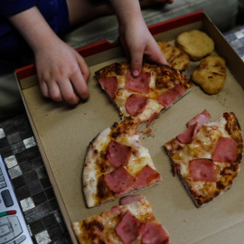 Foto de archivo de un niño cenando pizza.