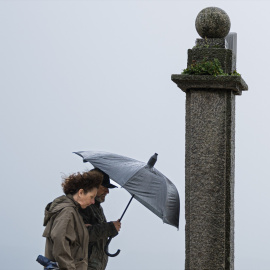 Foto de archivo de dos personas refugiándose de la lluvia en Galicia.
