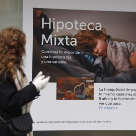 Una joven pasa por delante de un anuncio de hipotecas de una entidad bancaria.