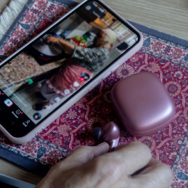 Un video reproduciéndose en un móvil al lado de unos auriculares.