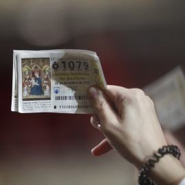 Una mujer agarra sus décimos antes de que comience el Sorteo Extraordinario de la Lotería de Navidad.