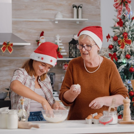 Una mujer mayor con una niña cocinando en vísperas de las fiestas de Navidad.