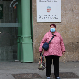 Una dona davant l'entrada principal de l'hospital Clínic, amb la mascareta posada
