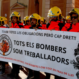 Diversos bombers voluntaris sostenent una pancarta on es pot llegir 'tots els bombers som treballadors'