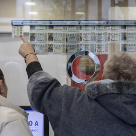 Una señora le indica al lotero el décimo que quiere.