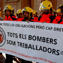 Varios bomberos voluntarios sosteniendo una pancarta en la que se puede leer "todos los bomberos somos trabajadores".