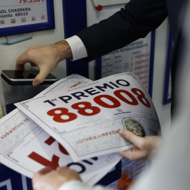 El propietario de la administración sujeta el cartel del primer premio.