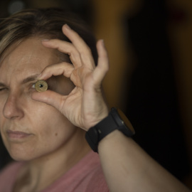 Una mujer mira a través de una moneda de las antiguas pesetas, en una imagen de archivo.