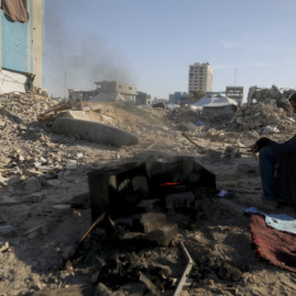 Una mujer prepara comida entre los escombros y las bombas israelíes sin detonar en una antigua base militar de Hamás en Gaza (19/04/2025)