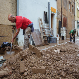 Dues persones netegen baixos i un carrer afectats pel temporal de pluges a Santa Bàrbara