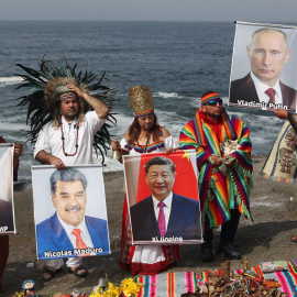 Un grupo de chamanes y curanderos sostienen imágenes de varios lideres mundiales durante un ritual de fin de año frente al océano Pacífico, en Lima (Perú).