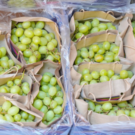 Fotografía de archivo de racimos de uvas en un expositor de una frutería en un mercado.