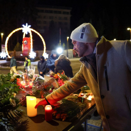 Un hombre pone una vela en el velatorio improvisado por las víctimas del incendio de Le Constellation.