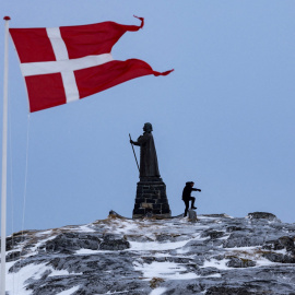 Un hombre camina junto a la bandera danesa que ondea en Nuuk, Groenlandia (Archivo).
