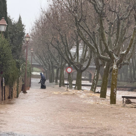 Un home passa per un carrer de Peratallada inundat d'aigua
