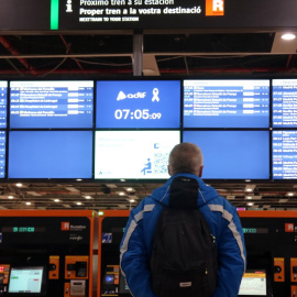Un passatger mira les pantalles amb els horaris de Rodalies a l'estació de Sants. 23/01/2026