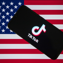 Fotografía de archivo del logotipo de TikTok en la pantalla de un teléfono móvil con la bandera estadounidense de fondo.