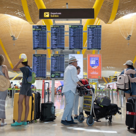 Foto de archivo. Pasajeros con maletas visualizan las pantallas, en el Aeropuerto Adolfo Suárez Madrid-Barajas.