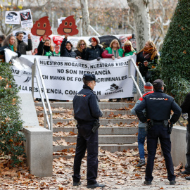 Dos policías observan a los miembros de la plataforma Stop Deshaucios que se concentran frente a la Audiencia Nacional de Madrid.