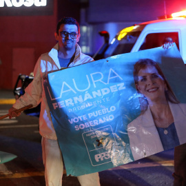 Dos seguidores del derechista Partido Pueblo Soberano sostienen una pancarta con la imagen de su candidata y presidenta electa de Costa Rica, Laura Fernández.