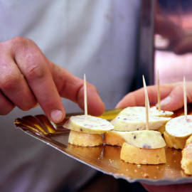 Detall d'unes mans agafant un pintxo de botifarra d'ou