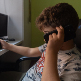 Un niño usa el teléfono móvil y una tablet