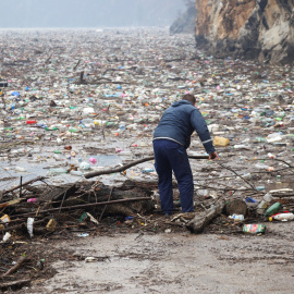 Un trabajador limpia la basura de un vertedero flotante en el río Drina, en Bosnia Herzegovina.