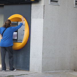 Una mujer saca dinero en un cajero automático.