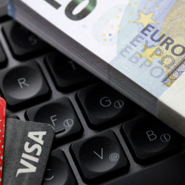 Una ilustración con billetes de euro, tarjetas de crédito y un teclado.