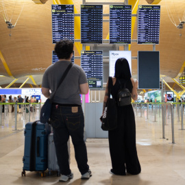 Imagen de archivos de personas mirando las pantallas informativas en la T4 del Aeropuerto Adolfo Suárez Madrid-Barajas.