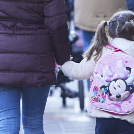 Una niña, pasea de la mano acompañada de su madre.