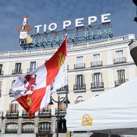 Una bandera de Castilla y León, frente al anuncio de Tío Pepe, durante un acto reivindicativo de Jóvenes de Castilla y Léon contra la despoblación, en la Puerta del Sol, a 5 de febrero de 2022,