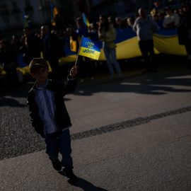 Un niño con una bandera de Ucrania encabeza una manifestación en protesta contra la guerra de Rusia.