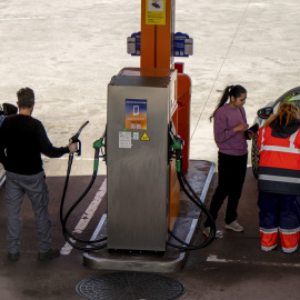 Varias personas repostan combustible en sus vehículos en una gasolinera