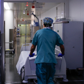 Un celador transporta una camilla vacía en el pasillo.