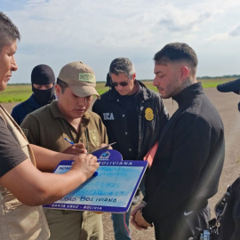 Fotografía cedida por la Policía de Bolivia del uruguayo Sebastián Marset (cd) antes de abordar un avión tras su captura este viernes en Santa Cruz (Bolivia).