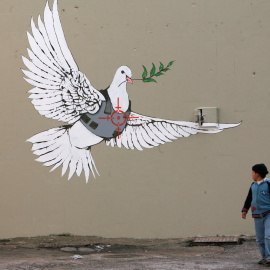 Un niño palestino observa una de las pintadas por el artista callejero británico Banksy en la ciudad de Belén, en Cisjordania.