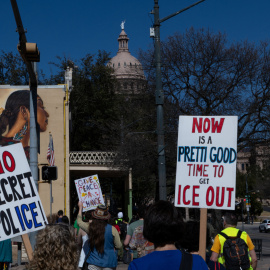 Personas portan pancartas y marchan hacia el Capitolio de Texas contra el ICE.