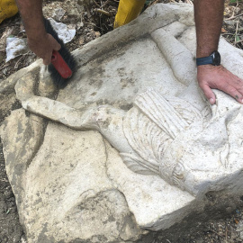 Un operario limpia uno de los bloques decorados pertenecientes a un monumento funerario cerca de la Vía Apia, al sur de Italia.
