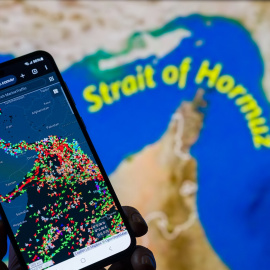 Ilustración que muestra el movimiento de buques en el estrecho de Ormuz en un móvil con un mapa de fondo.