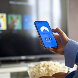 Una persona mira el móvil mientras se prepara para ver una película en casa.