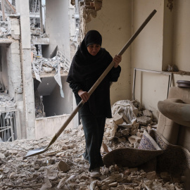 Una mujer trata de limpiar una vivienda en el barrio de Haft Chenar de Teherán que resultó dañada en un ataque de Estados Unidos e Israel.