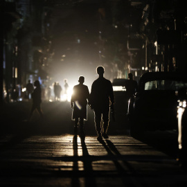 Personas caminan por una calle sin electricidad este sábado, en La Habana (Cuba).