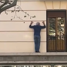 Un señor encaramado a una fachada.