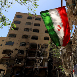 Imagen de una bandera de Irán cercana a un edificio dañado, en Teheran.