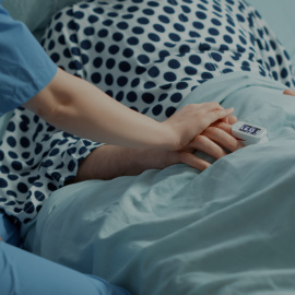 Enfermera cogiendo la mano de un paciente en el hospital.