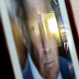 El fiscal general Todd Blanch reflejado en una fotografía del Presidente Donadls Trumo mientras se anuncia.
